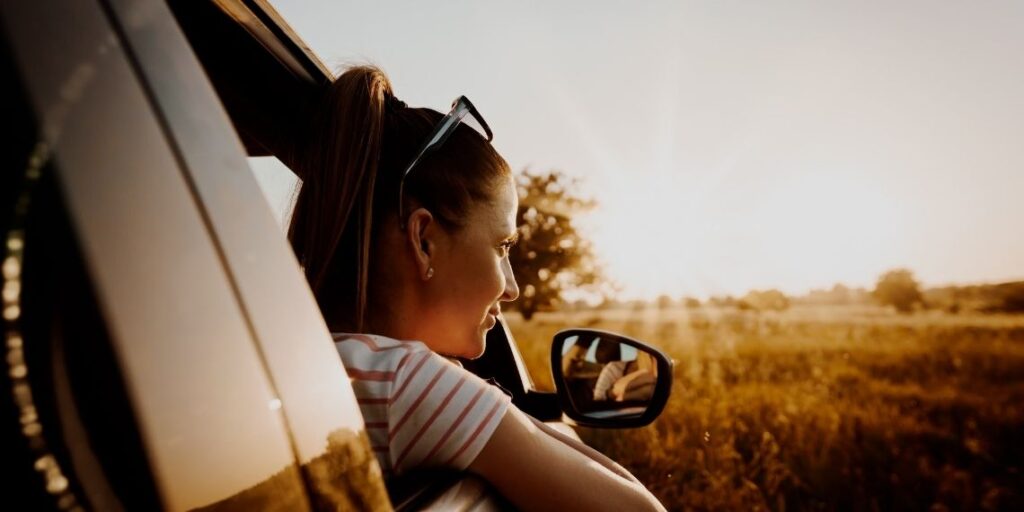 femme en voiture avec couché de soleil