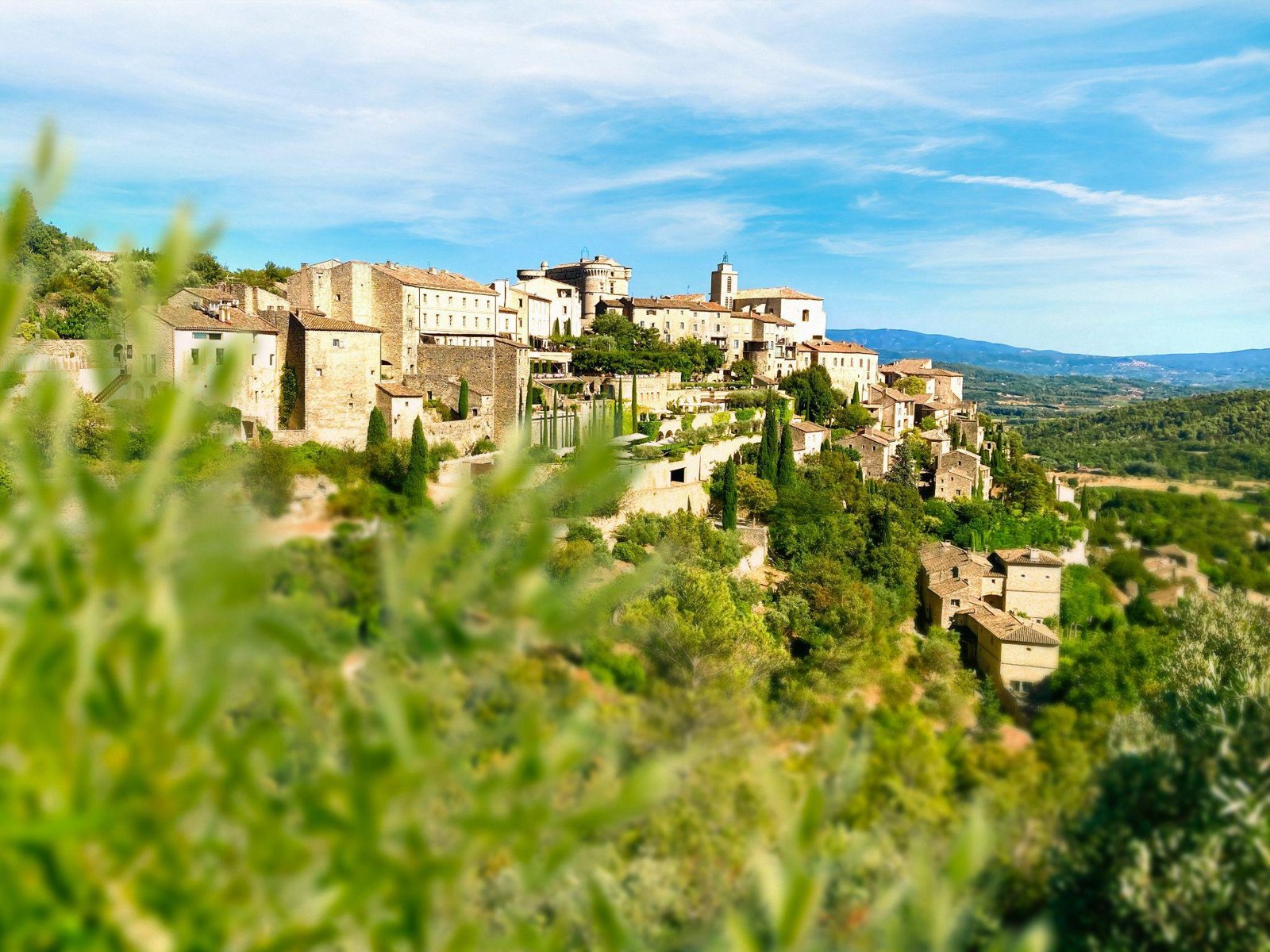 Un village de pierre perché sur une colline sous un ciel bleu.